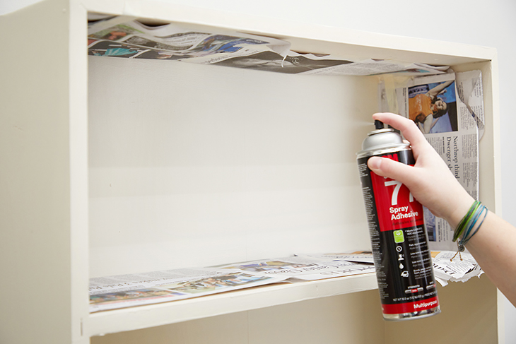Carefully apply adhesive spray to the back of one shelf.